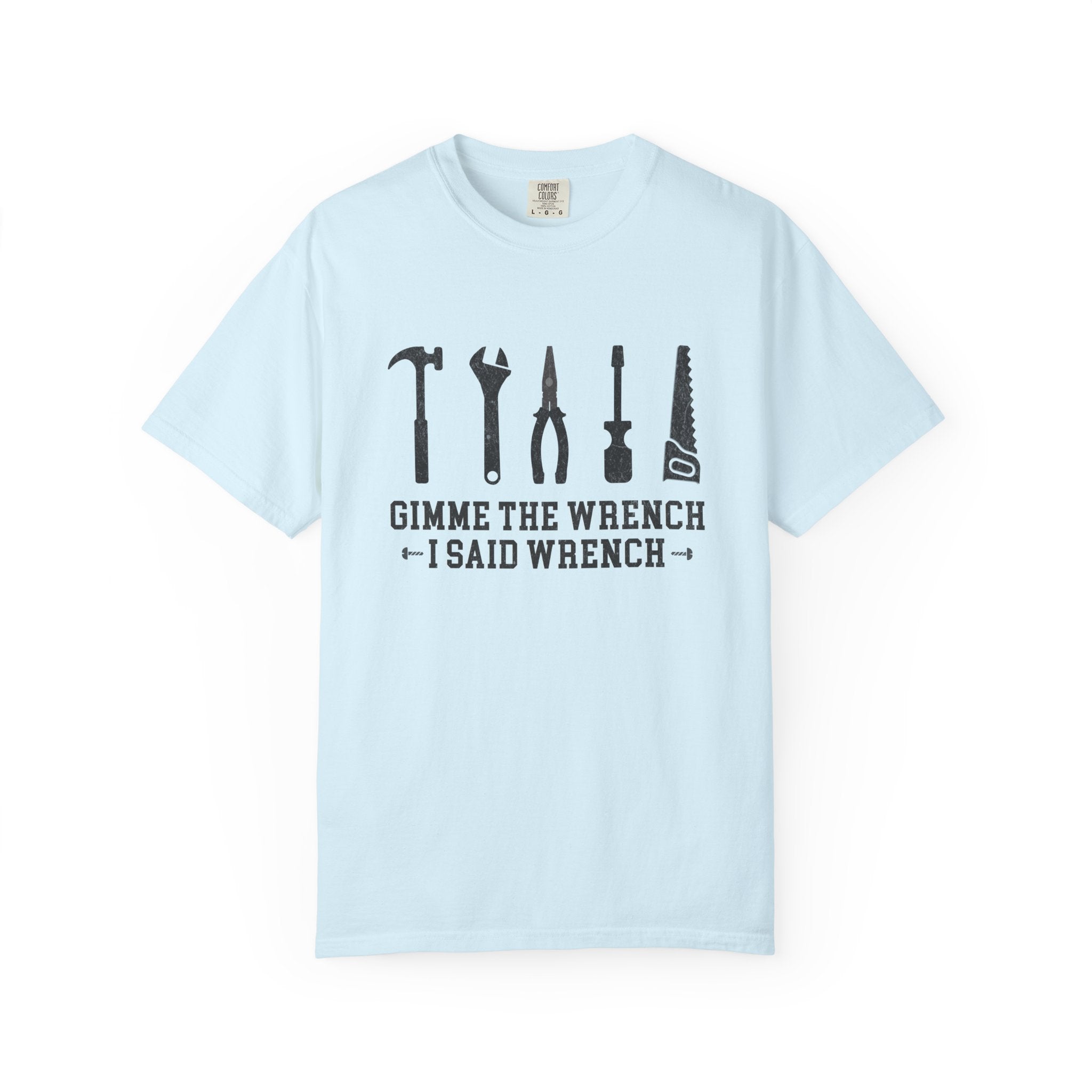 A light blue crewneck t-shirt with a black graphic of various hand tools (hammer, wrench, pliers, screwdriver, saw) and the text 'GIMME THE WRENCH I SAID WRENCH' printed on the chest, displayed on a clean white background.