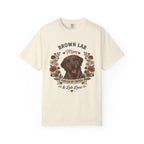 An off-white short-sleeve crewneck t-shirt featuring a graphic print of a brown Labrador Retriever with the text 'BROWN LAB Mom' and 'FUELED BY COFFEE & Lab Love' surrounded by a floral wreath.