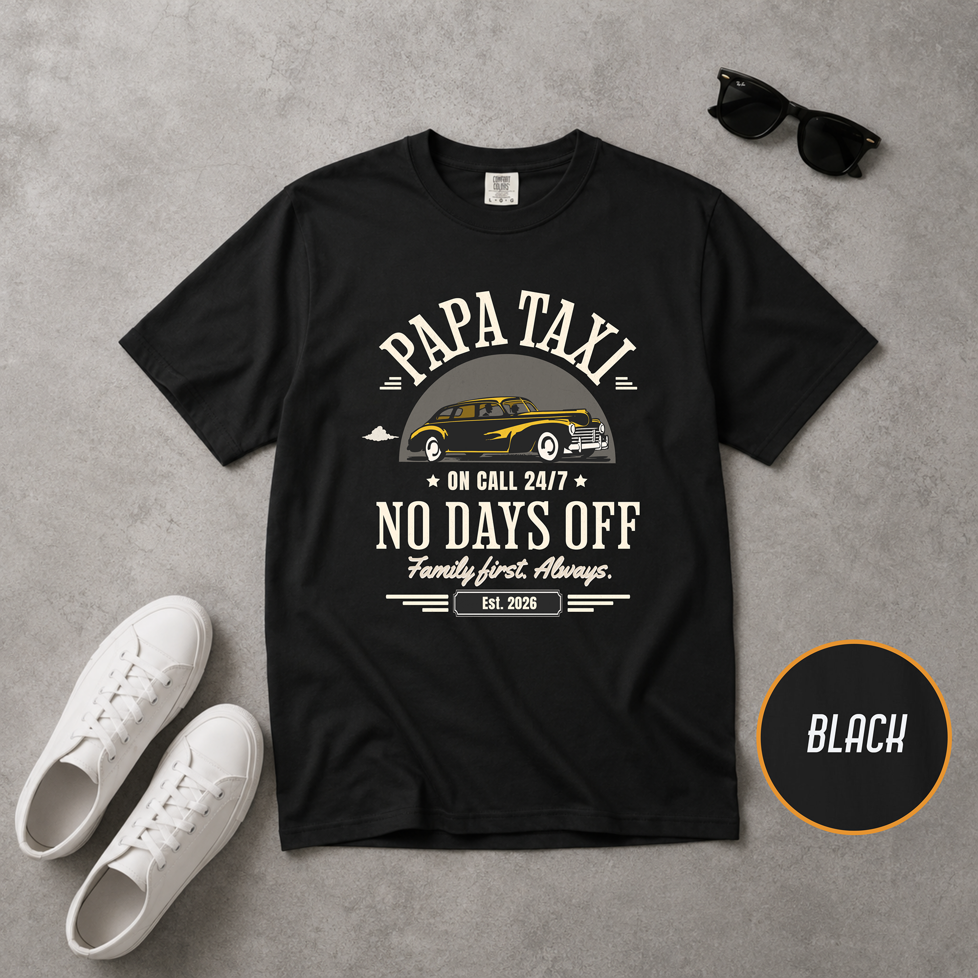 Black t-shirt with 'Papa Taxi' graphic and text on a gray surface with white sneakers and sunglasses.