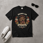 Black t-shirt with brown lab graphic and text on a gray surface with white sneakers and sunglasses.